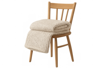 Soft knitted blanket draped over rustic wooden chair, creating inviting home interior atmosphere