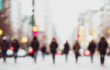Blurred figures walk on a city street with buildings and lights in background.Premium urban photos for poster, banner and pamphlet backgrounds