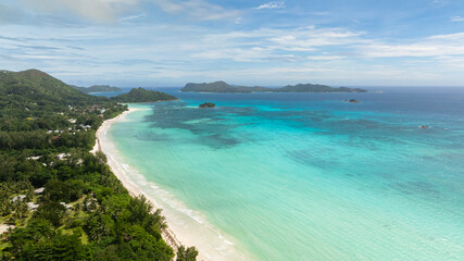 Lagoon with rich shades of blue and green, framed by sandy shores and tropical vegetation. Anse Volbert Beach. Praslin, Seychelles.