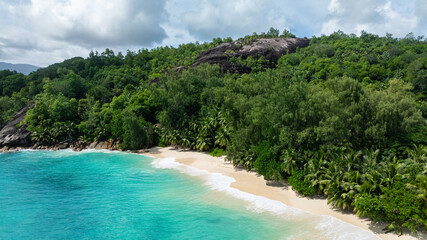 A beautiful beach with a turquoise bay surrounded by lush vegetation. Seychelles, Mahe. Anse Soleil Beach.