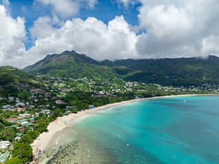 Curved sandy beach with mountainous surroundings, crystal clear waters and gentle waves. Seychelles, Mahe. Beau Vallon Beach.