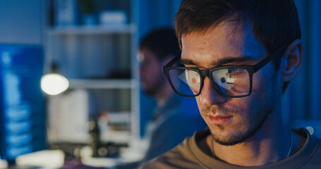 Closeup team adult male freelance work late typing write prompt AI bot app program nomad terminal code at office night. Artificial intelligence dashboard, robotics, user interface, machine learning.