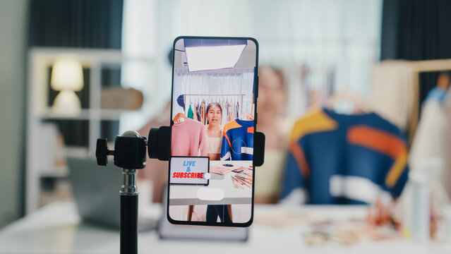 Close-up phone screen record Asia lady vlogger look phone camera review sweater new collection live selling online in IG story reel tiktok work at home studio. Business online media concept.