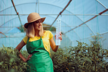 Farmer Holding a Thermometer Showing the Temperature in a Greenhouse. Agricultural worker controls temperatures in a greenhouse 

