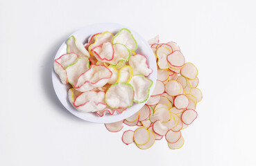 Raw and deep-fried kerupuk bawang or Garlic crackers in a white bowl, an Indonesian cracker made from tapioca flour and flavored with garlic or prawn and come in various edge colors. 