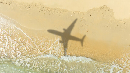 Aerial view of shadow passenger plane silhouette and sandy beach blue sea with waves at sea beach...