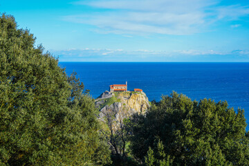 View through trees of San Juan de Gaztelugatxe church