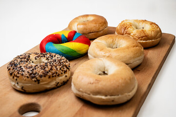 Closeup view of a collection of bagel breads with various kinds on a wooden board isolated over a white background