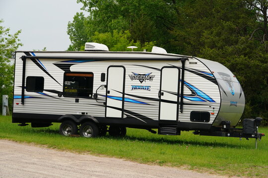 Different brand 5th wheel campers sit outside being stored for the season.