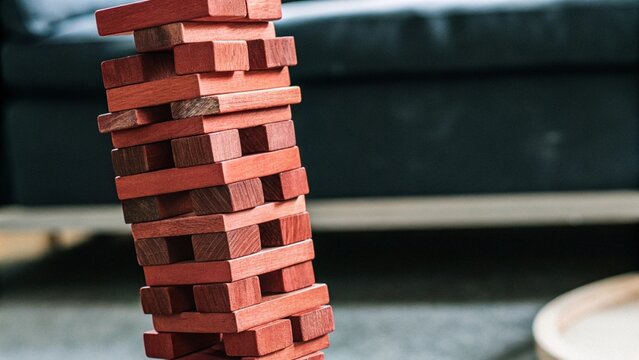 Close up wooden jenga toy block tower unstable structure tension concept falling moment background
