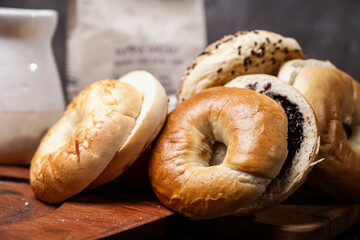 Closeup view of a variety of kinds of bagel breads with sliced bagel bread on a wooden board