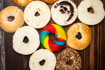Closeup view of a variety of kinds of bagel breads with bagel bread sliced on a wooden board. Top view