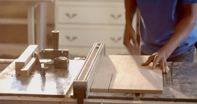 African American man using chisel on wooden board on shop workbench, with clamp handle, copy space