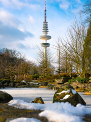 Fernsehturm/Heinrich-Hertz-Turm Hamburg in verschneiter Landschaft, Blick vom Japanischen Garten im Park Planten un Blomen, vertikal