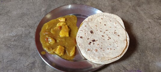 The image shows a plate of Matar Paneer with Roti, a popular North Indian dish. Matar Paneer consists of paneer Indian cheese and peas cooked in a tomato based sauce, spiced with garam masala. 