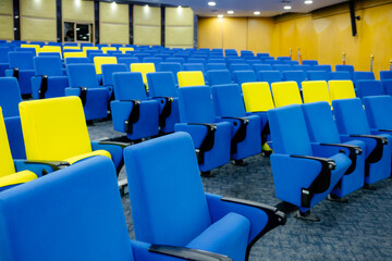 Naklejka premium An empty modern conference room is lined with rows of blue and yellow chairs.