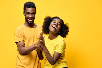 Fototapeta premium Joyful young couple in matching yellow shirts, celebrating happiness and love against a vibrant yellow backdrop