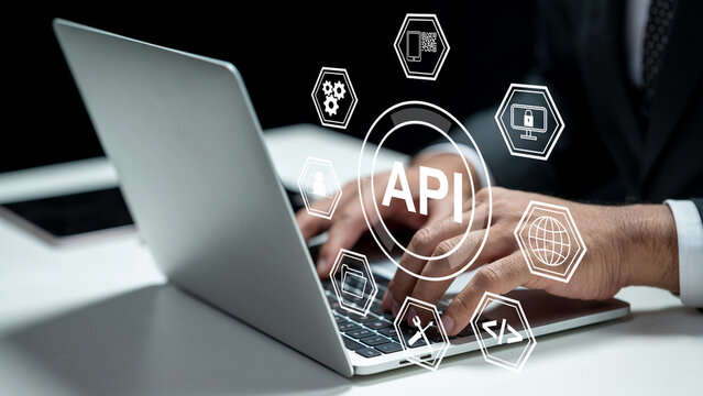Businessman using a laptop while showing an icon of API. Tablet on the table. Technology innovation on a virtual screen. Concept of Application Programming Interface - Powered by Adobe