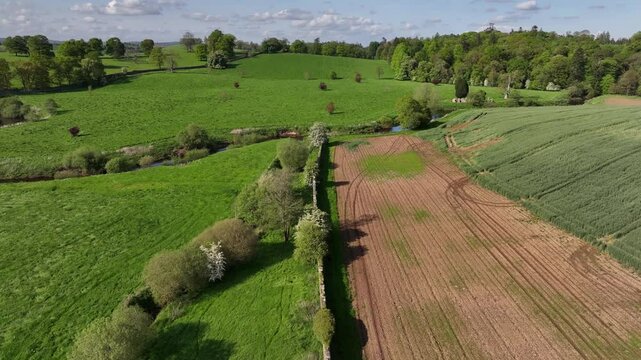 Caledon Border Wall, County Tyrone, Northern Ireland, May 2023. Drone forward motion over stone heritage, flowing river, farmlands and lush forests countryside, natural beauty.