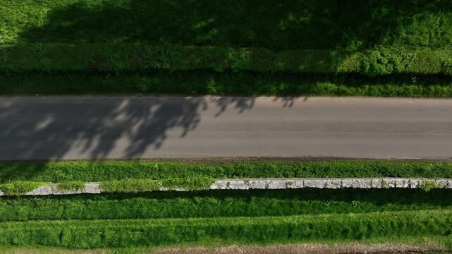 Caledon Border Wall, County Tyrone, Northern Ireland, May 2023. Drone top-down view moving right over stone heritage dividing farmlands, country road, green fields and clean aerial symmetry.