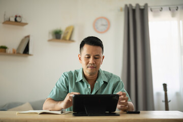 Man Engaged in Working from Home Setting with Tablet Device in Modern Stylish Interior, Focusing on Productivity and Comfort in Daily Life