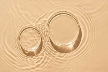 Minimalist top-down scene of two clear circular glass podiums submerged in calm beige water.Styled for skincare product mockups, wellness branding, or modern beauty stock 