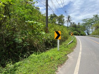 Editorial: Tropical Winding Road Curve Warning Signs. Curved coastal road with yellow and black...