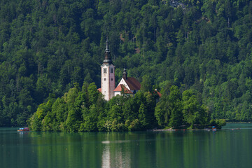Church of the Assumption on Bled Island reflecting in calm Lake Bled waters, Slovenia