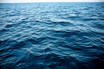 Gentle ocean waves gently rolling over a deep blue water surface under a clear sky