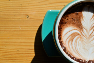 Top view of hot chocolate with latte art in the green gauze cup. Wooden table, black, dark, shadow, copy space, empty, free. Half, extreme close up.