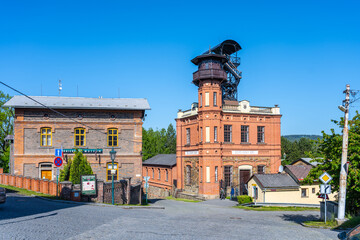 Historic structures of Sevcinsky mine in Brezove hory showcase Czechia's mining heritage. Bright sky illuminates the vibrant brickwork, with well-maintained landscaping enhancing the site.