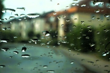 Abstraktes Motiv mit Regentropfenmuster vor Straße und Wohnhäusern in Kleinstadt bei Regen am Nachmittag im Frühling