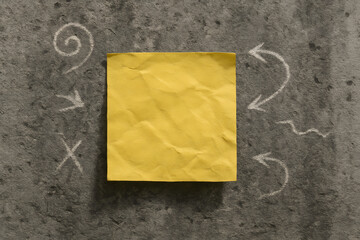 Single Crumpled Sticky Note on Concrete Wall with Chalk Drawings