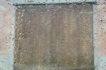 Abstraktes Motiv mit Regentropfenmuster auf Glasscheibe vor Fassade von alter Bauernscheune mit...