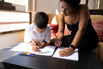 Fototapeta premium Teacher helping young student drawing with colored pencils at home