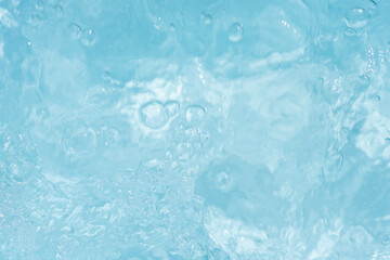 Obraz premium Blue water with ripples on the surface. Defocus blurred transparent blue colored clear calm water surface texture with splashes and bubbles. Water waves with shining pattern texture background.