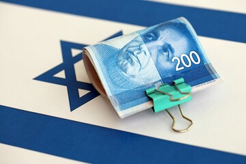Israel New Shekels banknotes on national flag. The current Israel money bills lies on flag in big...