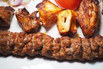 Delicious grilled Adana kebabs and vegetables on a plate