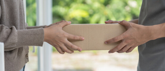 Happy smiling woman receives boxes parcel from courier in front house. Delivery man send deliver...