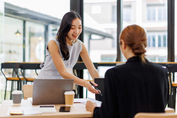 Two asian lady colleagues discussing new project, business asian women using digital tablet together in office
