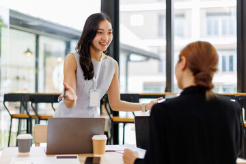 Two asian lady colleagues discussing new project, business asian women using digital tablet together in office
