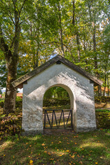 Old idyllic churchgate by a country road in a forest at autumn