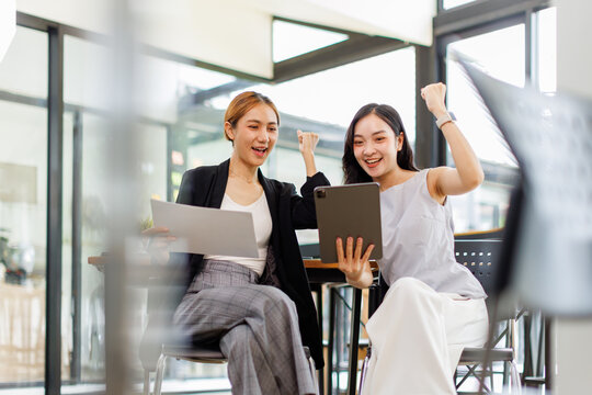 Two asian business women in teamwork discussing and using laptop in the office . Two excited happy asian business women are talking and consulting.
