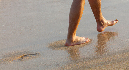 A man is walking on the beach with his feet in the water