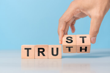 Businessman hand change wooden cube block with TRUST and TRUTH business word on table background. Trustworthy, Truth, beliefs and agreement concept
