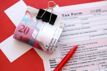 Swiss franc banknotes and tax form with pen. The current francs money bills lies on tax return form