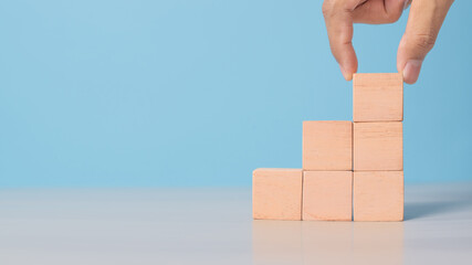 Close-up of hand aligning plain wooden cubes. Minimalist layout for planning, growth, or organization.