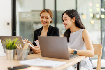 Two managers discussing contract in meeting room or modern office workplace.Two young pretty asia business woman work.