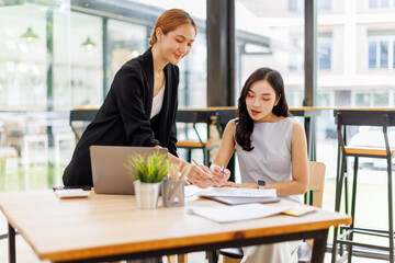 Two professional caucasian asian business women friends collaboration, working together at office,...