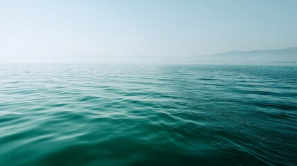 Fototapeta premium Serene midrange side view of calm blue sea surface with soft morning haze and blended horizon creating a tranquil ocean scene with copy space